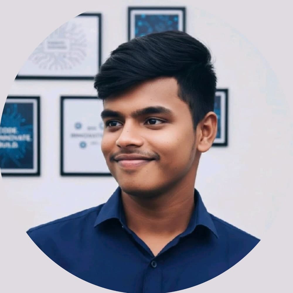 Revanth Kumar, smiling, in a navy shirt in front of framed tech prints.